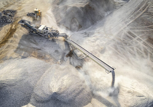 Aerial view of a quarry featuring heavy machinery and a conveyor belt in a dusty outdoor landscape in the Dominican Republic