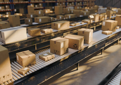 Rows of cardboard boxes and parcels travel along conveyor belts inside a large distribution warehouse in the Dominican Republic